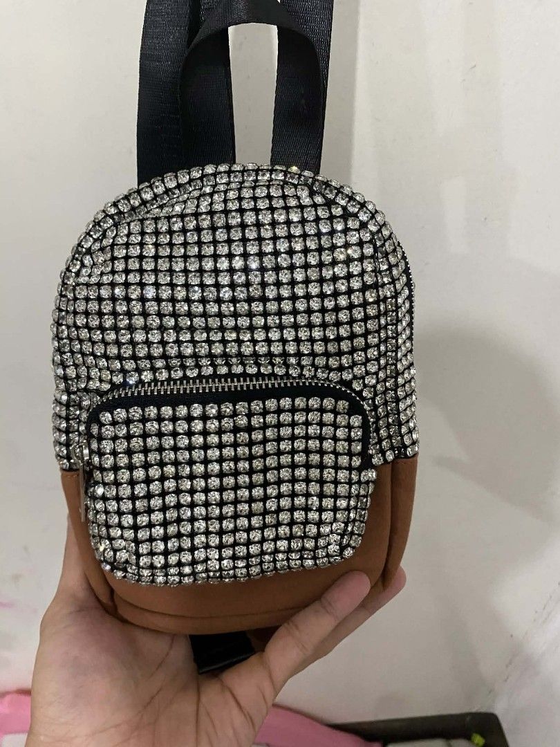 Alexander Wang cruiser embellished Mini Backpack sling (Category: Luxury Bags & Wallets) located in Pasig City. Submitted by psg2019 (Listing ID 1425558174, Image 3). Description: Mini backpack features a dazzling rhinestone exterior with a brown suede-like bottom. It has a front zippered pocket and a top zipper closure. The interior includes a brand tag. The backpack has black straps and silver-toned hardware. It's a stylish accessory for carryi