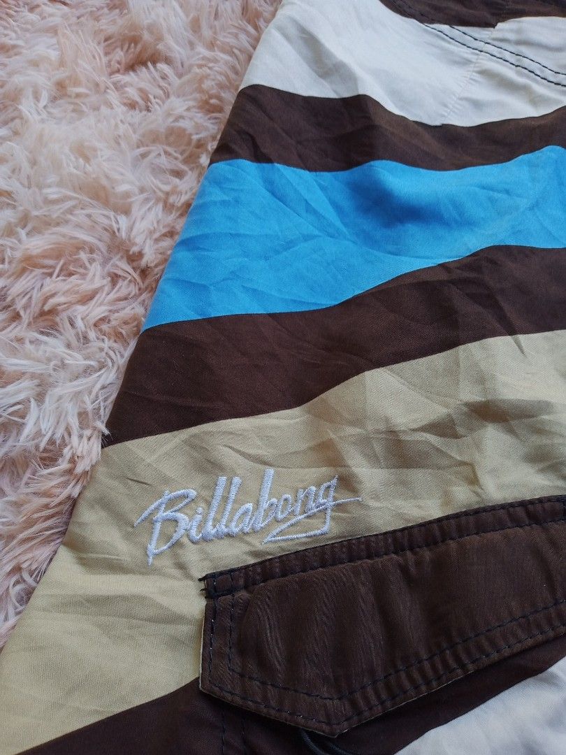 Billabong Board Shorts (Category: Swim Trunks & Board Shorts) located in Boston. Submitted by johnpaulvi30029 (Listing ID 1425476339, Image 3). Description: Stylish Billabong board shorts featuring a unique swirl design in brown, blue, and white. These shorts have a drawstring closure and a back pocket. The Billabong logo is embroidered on the front. Perfect for the beach or casual wear..