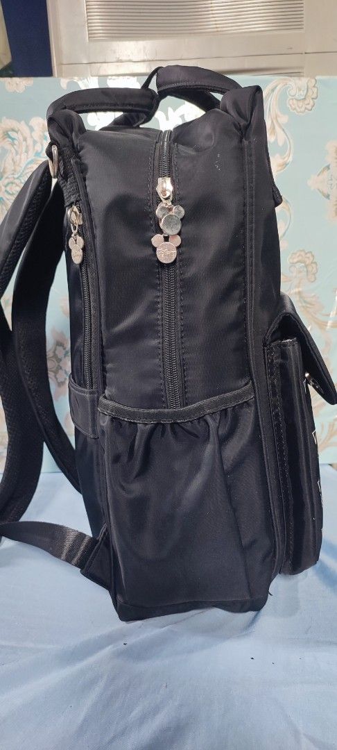 Disney Mickey Mouse Diaper Bag (Category: Diaper Bags & Wetbags) located in Manila. Submitted by mhitchz10 (Listing ID 1425519538, Image 3). Description: Black diaper bag featuring a Mickey Mouse design. It has a front flap with the word "Mickey" embroidered on it. The bag has multiple compartments, including side pockets and a spacious interior. It also has adjustable straps and a top handle for easy carrying. Dimensions are approximately L-16, 