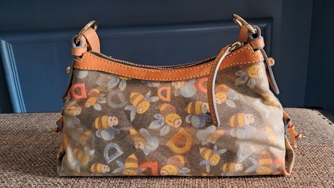 Dooney & Bourke Bee Print Handbag (Category: Clutches) located in Santa Rosa. Submitted by majanice (Listing ID 1425518851, Image 2). Description: Dooney &Bourke Pochette bag Bee print leather strap and trims very good hardware and leather canvass bag great addition to Dooney fan and collector! condition: very good leather and hardware clean inside flaw is mainly on the bag the canvass deteriorated in its color .