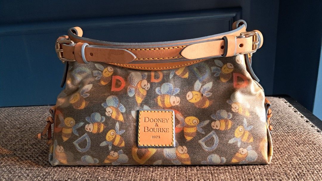 Dooney & Bourke Bee Print Handbag (Category: Clutches) located in Santa Rosa. Submitted by majanice (Listing ID 1425518851, Image 1). Description: Dooney &Bourke Pochette bag Bee print leather strap and trims very good hardware and leather canvass bag great addition to Dooney fan and collector! condition: very good leather and hardware clean inside flaw is mainly on the bag the canvass deteriorated in its color .
