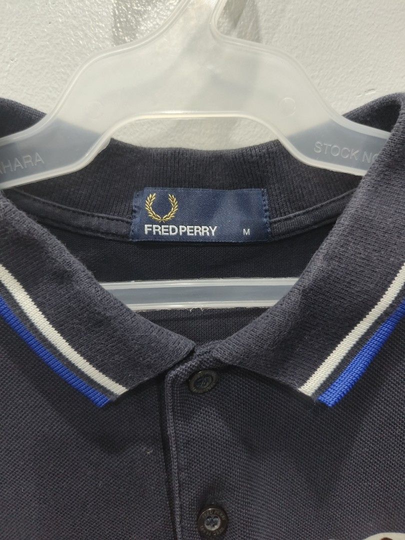 Fred Perry Polo Shirt - Navy Blue (Category: Tshirts & Polo Shirts ) located in Leyte. Submitted by chaem89 (Listing ID 1425582512, Image 3). Description: Authentic Fred Perry polo shirt in navy blue. Features a classic polo collar with blue and white trim on the collar and sleeves. The shirt has the iconic Fred Perry logo on the chest. Made in China. - Very Good Cond (slight fade on neck: pls refer to photo) - Size M on tag 20x26.