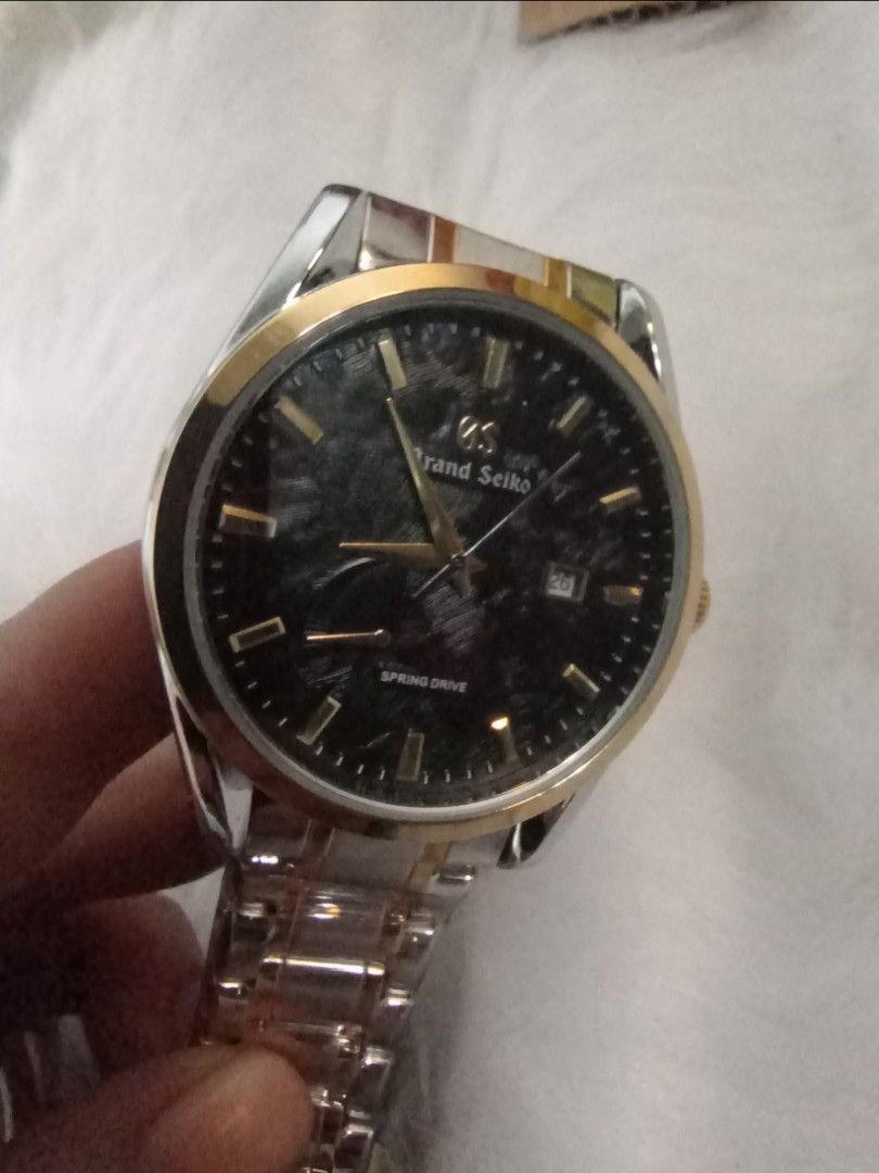 Grand Seiko Spring Drive Watch (Category: Luxury Watches) located in Manila. Submitted by crustynico23 (Listing ID 1425492062, Image 3). Description: Elegant Grand Seiko watch with a black dial and gold accents. Features a two-tone silver and gold bracelet. The watch has a visible automatic movement on the back. Includes a Seiko 5 tag. Made in Japan..