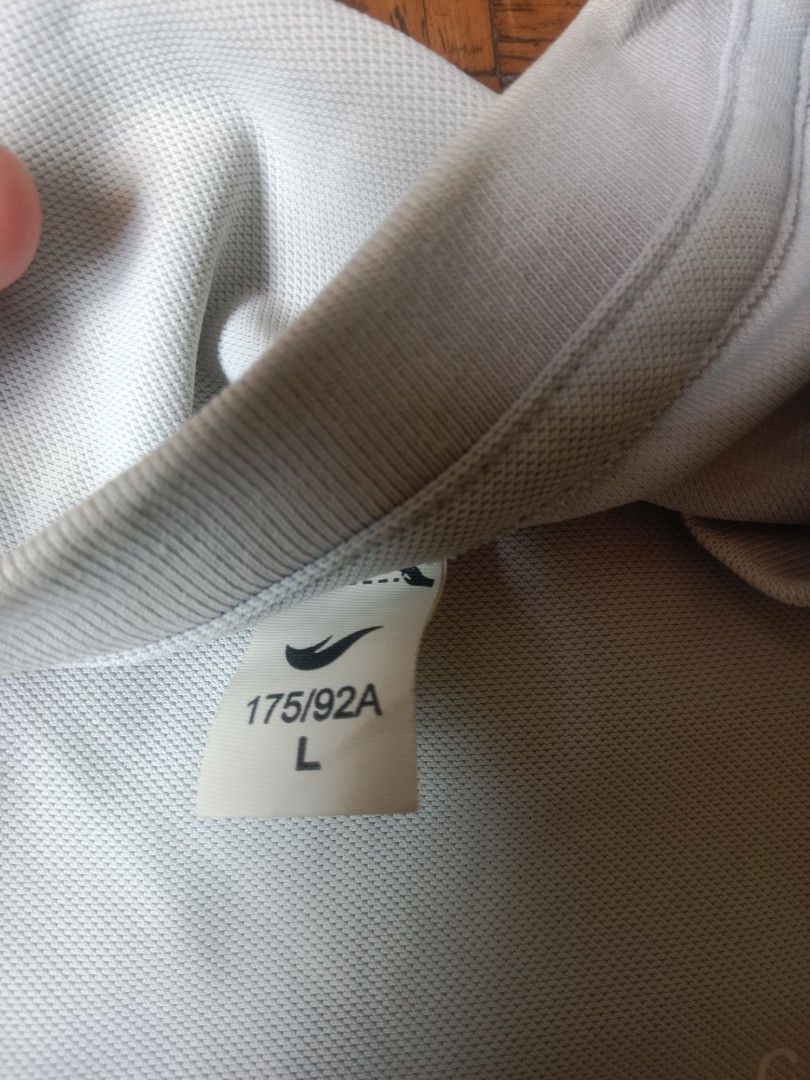 Gray T-shirt with Logo -M-L Size (Category: Tshirts & Polo Shirts ) located in Marikina City. Submitted by cathdeeee (Listing ID 1425560716, Image 2). Description: Gray t-shirt with a logo on the front. It has short sleeves and a crew neck. The shirt is laid flat on a wooden surface..