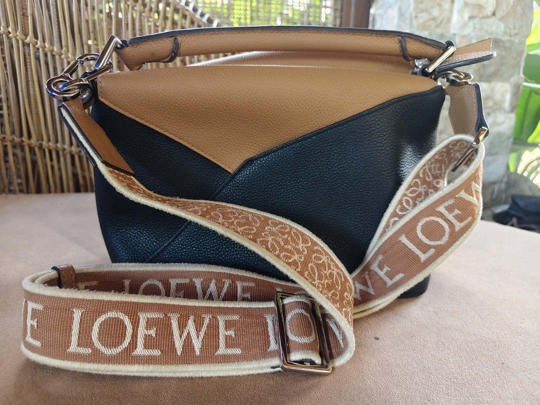 Loewe Puzzle Bag with Shoulder Strap (Category: Luxury Bags & Wallets) located in Camalig. Submitted by nasayaocat86662 (Listing ID 1417826910, Image 3). Description: - Loewe Puzzle Bag - Color block design: Black and tan leather - Detachable tan shoulder strap - Loewe logo on strap - Flap closure.