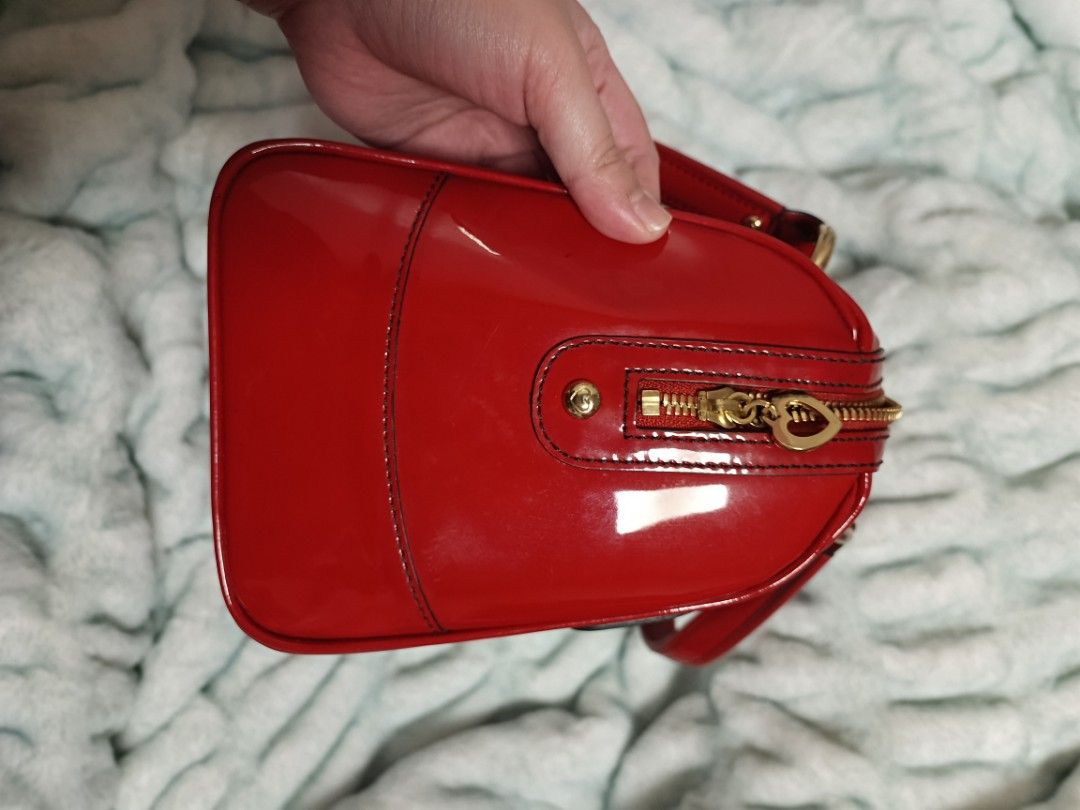 Lovecat Red Patent Leather Handbag (Category: Luxury Bags & Wallets) located in Batangas. Submitted by espresso.macchiato (Listing ID 1425535520, Image 3). Description: Lovecat handbag features a vibrant red patent leather exterior with gold-tone hardware. It has two front pockets with heart-shaped accents and a top zipper closure. The interior is lined with a patterned fabric. The bag has double top handles and a structured shape. Made in Korea.