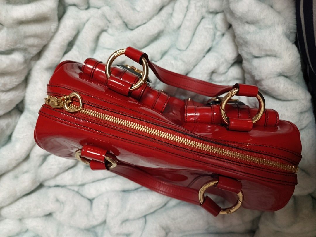Lovecat Red Patent Leather Handbag (Category: Luxury Bags & Wallets) located in Batangas. Submitted by espresso.macchiato (Listing ID 1425535520, Image 2). Description: Lovecat handbag features a vibrant red patent leather exterior with gold-tone hardware. It has two front pockets with heart-shaped accents and a top zipper closure. The interior is lined with a patterned fabric. The bag has double top handles and a structured shape. Made in Korea.