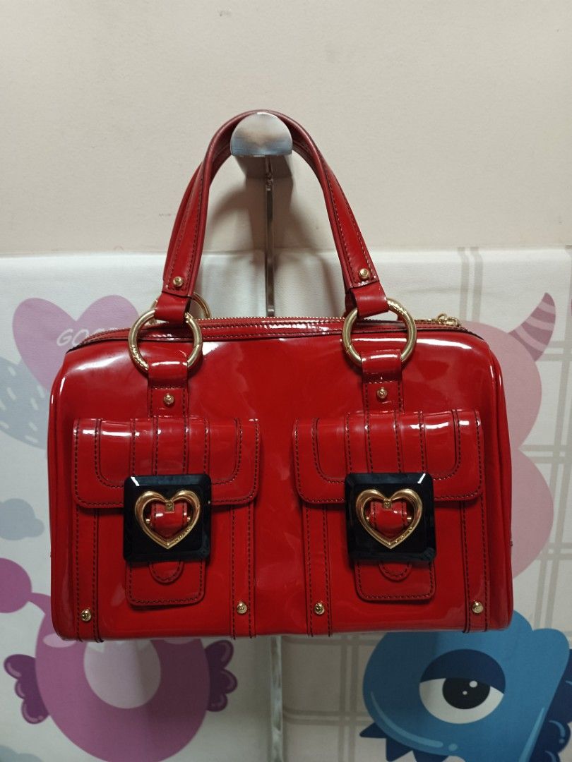 Lovecat Red Patent Leather Handbag (Category: Luxury Bags & Wallets) located in Batangas. Submitted by espresso.macchiato (Listing ID 1425535520, Image 1). Description: Lovecat handbag features a vibrant red patent leather exterior with gold-tone hardware. It has two front pockets with heart-shaped accents and a top zipper closure. The interior is lined with a patterned fabric. The bag has double top handles and a structured shape. Made in Korea.