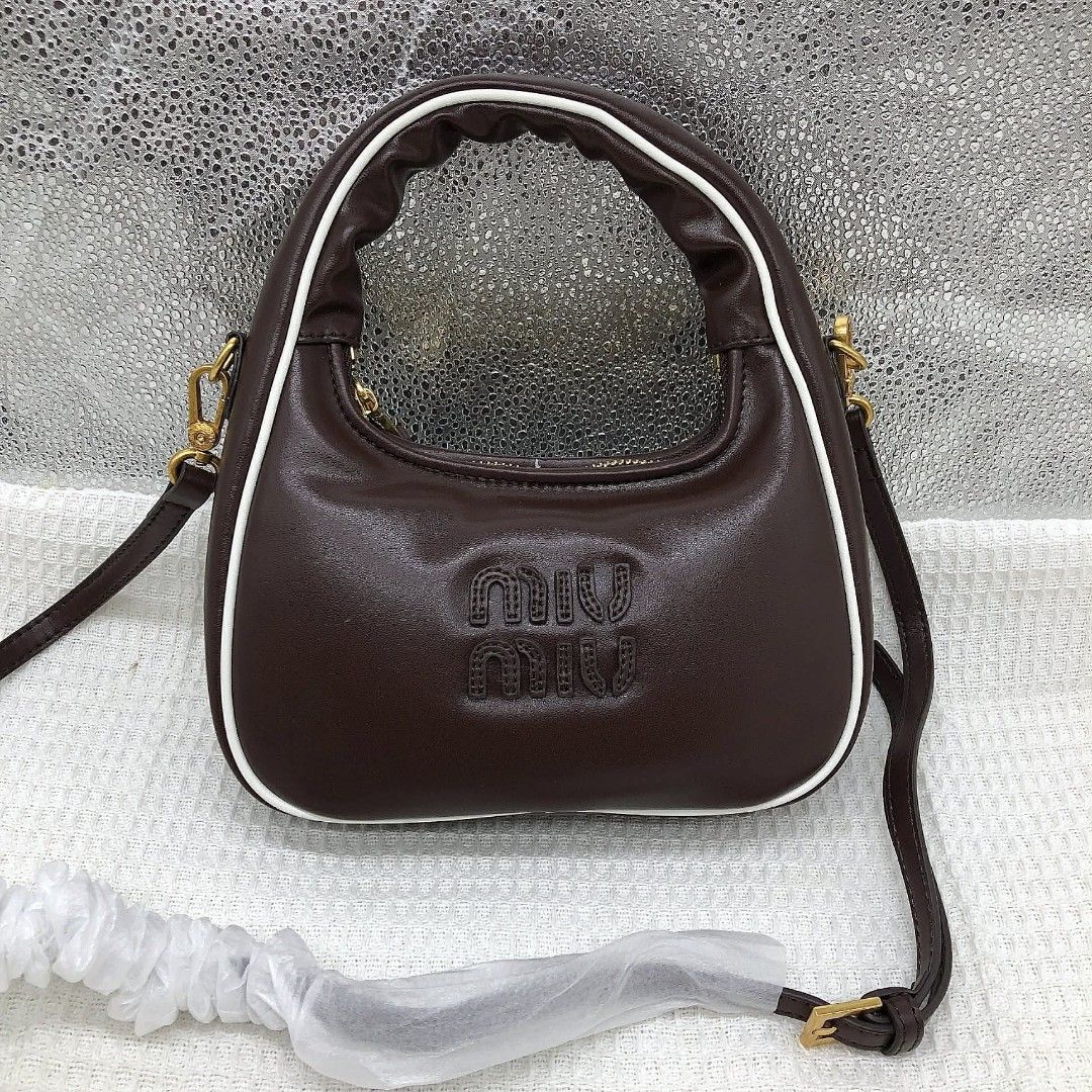 Miu Miu Leather Hobo Bag (Category: Luxury Bags & Wallets) located in Bocaue. Submitted by bagsbyjayce (Listing ID 1425475540, Image 2). Description: Miu Miu handbag features a brown leather exterior with a white trim. It has a top handle and a detachable shoulder strap. The bag has a zipper closure and a gold-tone hardware. The interior is lined with a satin-like fabric. The Miu Miu logo is embossed on the front of the bag..