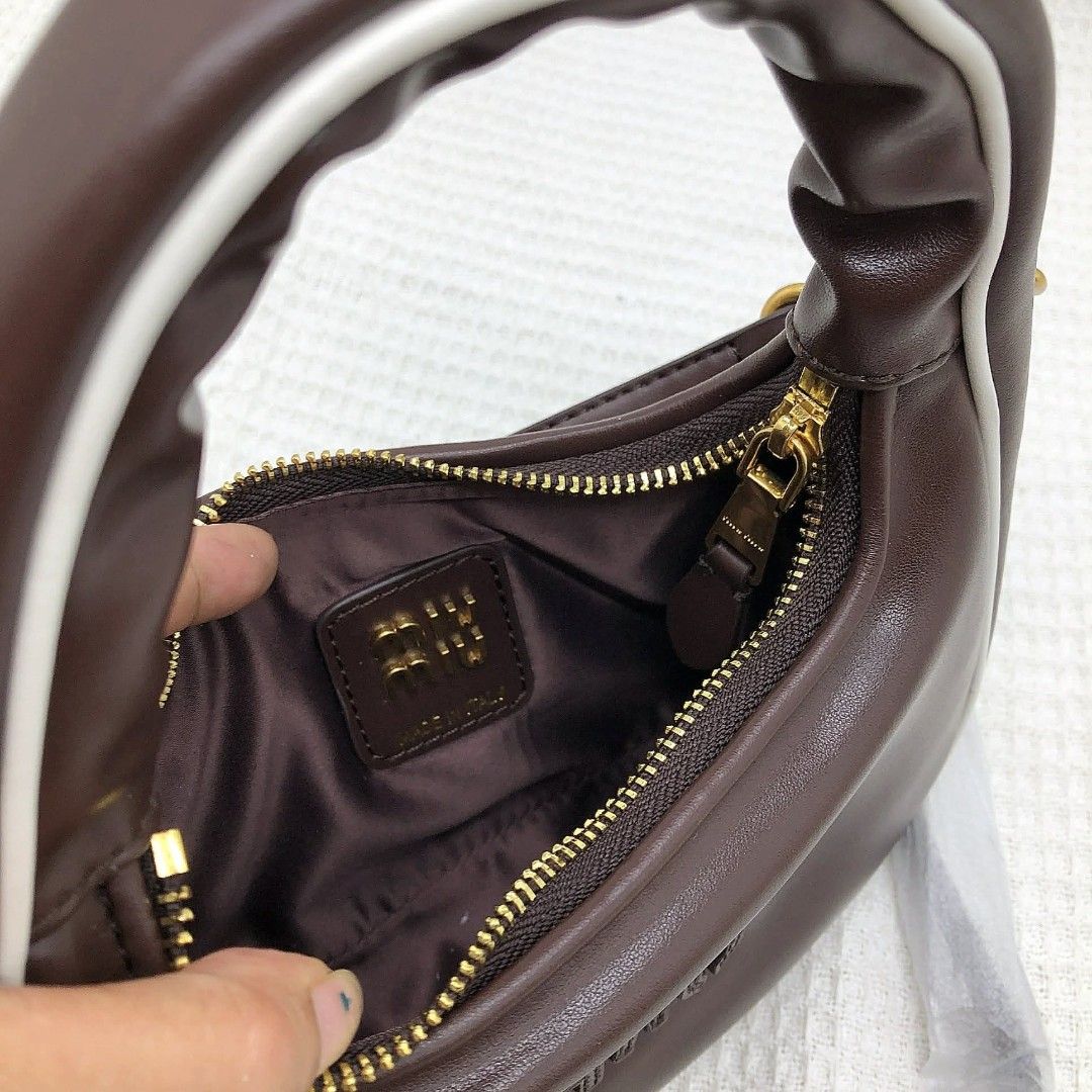 Miu Miu Leather Hobo Bag (Category: Luxury Bags & Wallets) located in Bocaue. Submitted by bagsbyjayce (Listing ID 1425475540, Image 3). Description: Miu Miu handbag features a brown leather exterior with a white trim. It has a top handle and a detachable shoulder strap. The bag has a zipper closure and a gold-tone hardware. The interior is lined with a satin-like fabric. The Miu Miu logo is embossed on the front of the bag..
