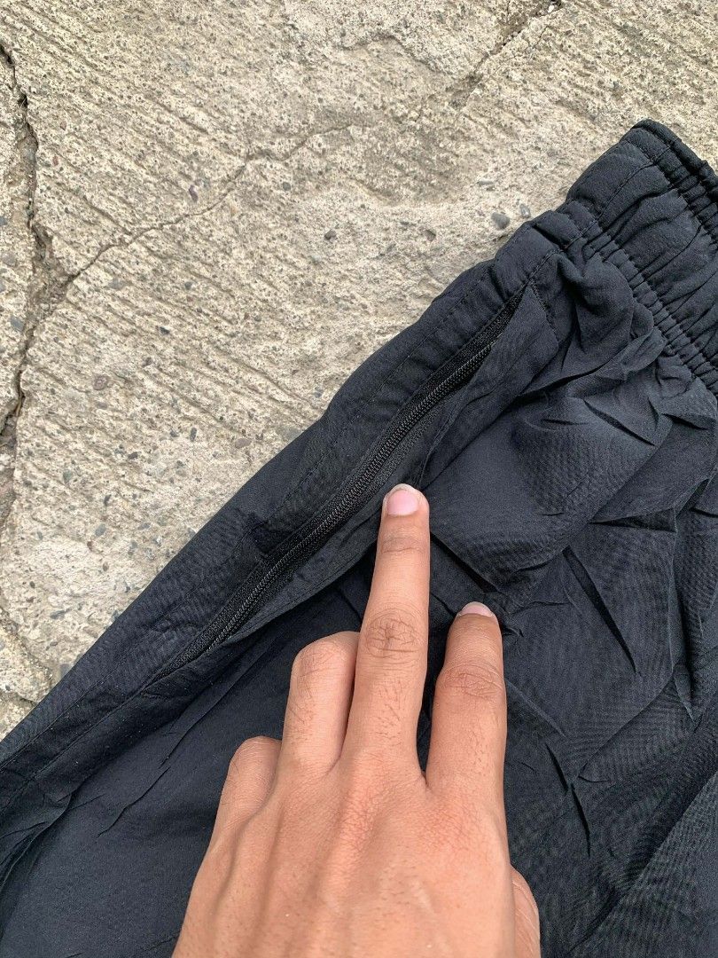 Nike Dri-FIT Black Pants baggy type (Category: Joggers) located in Manila. Submitted by louiseluch69680 (Listing ID 1425470350, Image 3). Description: Black Nike Dri-FIT pants. Features a Nike logo on the front and a drawstring waistband with the Nike logo. Includes zippered pockets. The tag indicates the pants are made in China and are size L. The material is 100% polyester. The pants are designed for comfort and performance. excellent condition