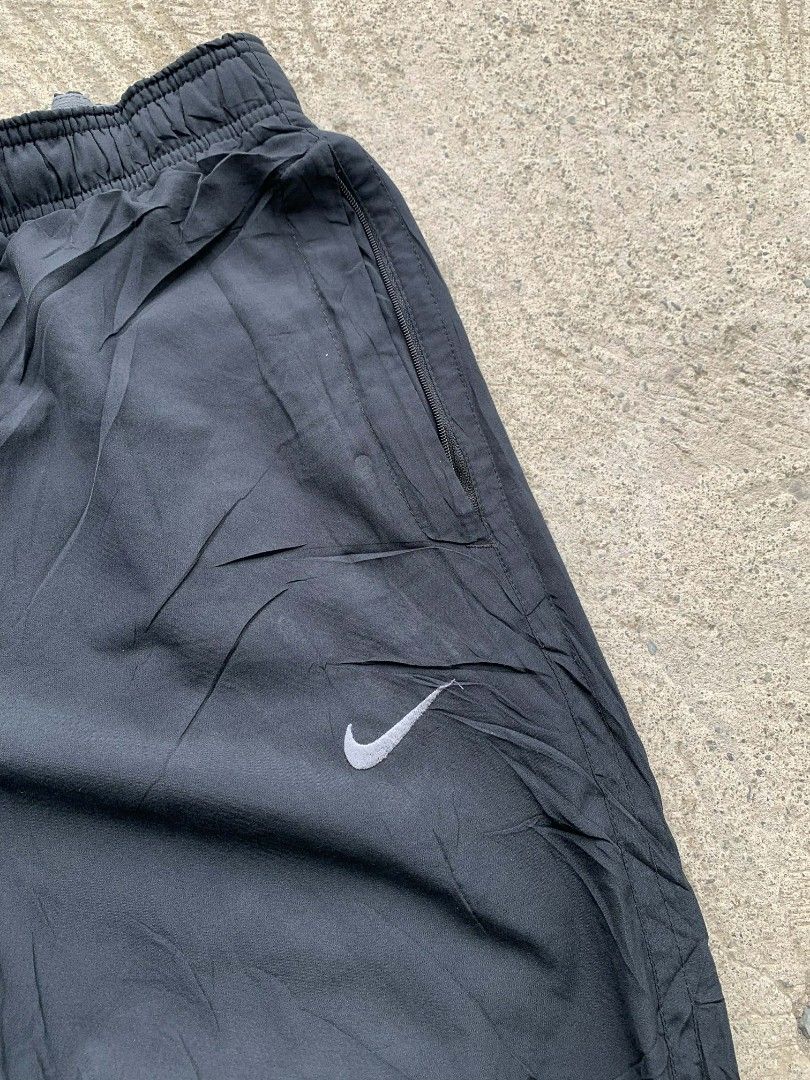Nike Dri-FIT Black Pants baggy type (Category: Joggers) located in Manila. Submitted by louiseluch69680 (Listing ID 1425470350, Image 2). Description: Black Nike Dri-FIT pants. Features a Nike logo on the front and a drawstring waistband with the Nike logo. Includes zippered pockets. The tag indicates the pants are made in China and are size L. The material is 100% polyester. The pants are designed for comfort and performance. excellent condition
