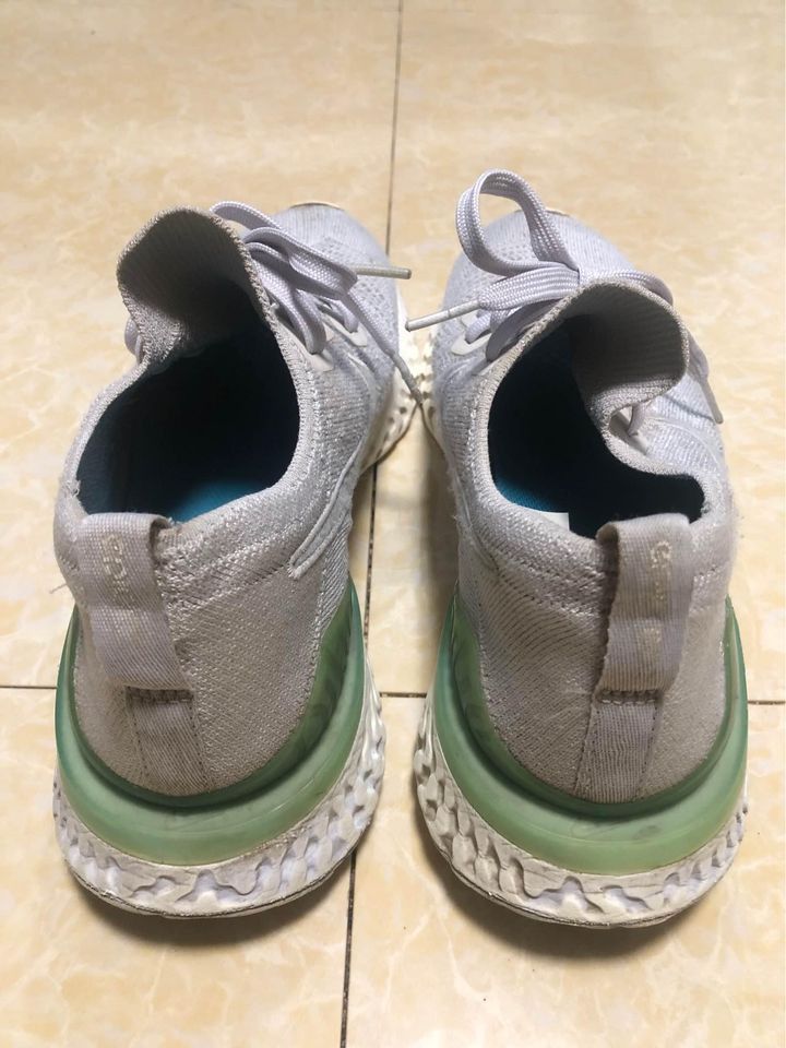 Nike Epic React Flyknit 2 'Vast Grey Blue Lagoon' US9 (Category: Sneakers) located in Mandaluyong City. Submitted by alexis_77 (Listing ID 1425492657, Image 2). Description: Nike Epic React Flyknit running shoes in a light grey color. Features a knit upper, lace-up closure, and a React foam midsole. The shoes have a green accent on the heel and a white sole. The Nike swoosh logo is visible on the side of the shoe. Stocked and stored. Buy at your 