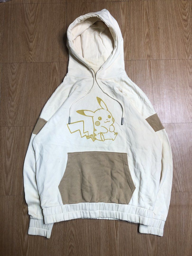 Pikachu Hoodie (Category: Hoodies) located in Quezon City. Submitted by yeahsource222 (Listing ID 1425623312, Image 1). Description: Cream-colored hoodie featuring a Pikachu design on the front and back. The front has a Pikachu graphic and a kangaroo pocket. The back displays the number "025" with Pikachu illustrations and other numbers. It has a drawstring hood and ribbed cuffs and hem. The sleeves have brown patches..