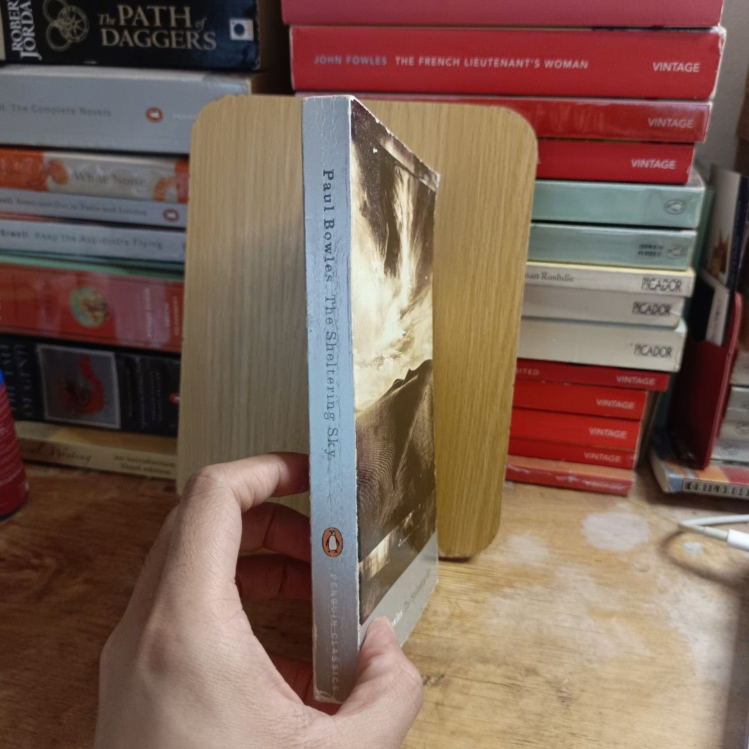 The Sheltering Sky by Paul Bowles (Category: Storybooks) located in Manila. Submitted by shelfenjoyment (Listing ID 1425503166, Image 2). Description: Copy of Paul Bowles' "The Sheltering Sky" published by Penguin Classics. The book features a cover with a desert landscape. The back cover includes a quote from the Evening Standard. The book has an introduction by Michael Hofmann..