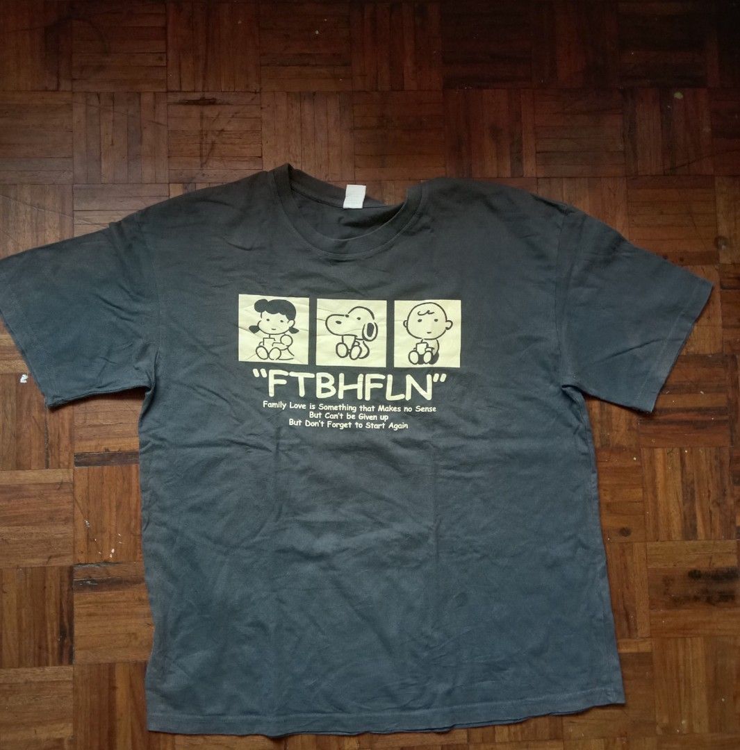 Vintage Snoopy Graphic T-shirt (Category: Tshirts & Polo Shirts ) located in Marikina City. Submitted by cathdeeee (Listing ID 1425561920, Image 1). Description: Vintage t-shirt features a Snoopy graphic with the text "FTBHFLN". It has a crew neck and short sleeves. The shirt is a dark grey color. The graphic includes Snoopy and other Peanuts characters. The shirt also has a quote printed below the graphic..