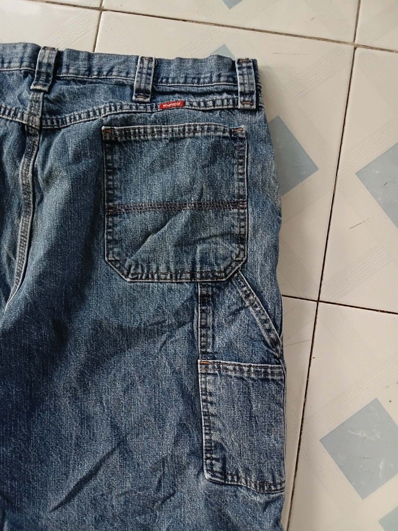 Wrangler Carpenter Denim Shorts - Size 40 (Category: Shorts) located in Gapan. Submitted by head.haven (Listing ID 1425562527, Image 3). Description: Classic Wrangler denim shorts. Features a carpenter style with multiple pockets. The shorts have a button closure and a standard five-pocket design. The size tag indicates a size 40. Made from denim material, these shorts are suitable for casual wear. The shorts have a faded blue color..