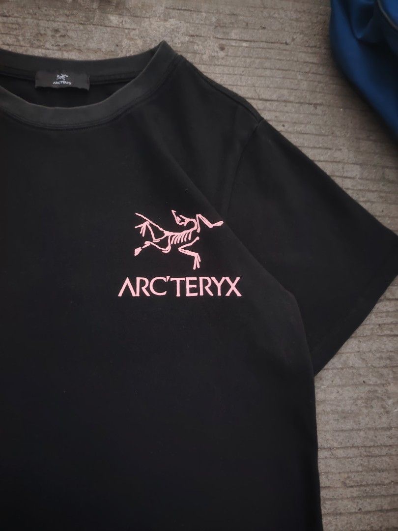 Arc'teryx T-shirt Big Logo (Category: Tshirts & Polo Shirts ) located in Calamba. Submitted by madskies (Listing ID 1429596682, Image 2). Description: Black Arc'teryx T-shirt with pink logo. Includes a blue Nike duffel bag with a red swoosh. The T-shirt has the Arc'teryx logo on the chest and the brand label on the neck. The bag has a top handle and a zipper closure. Both items are visible in the images..