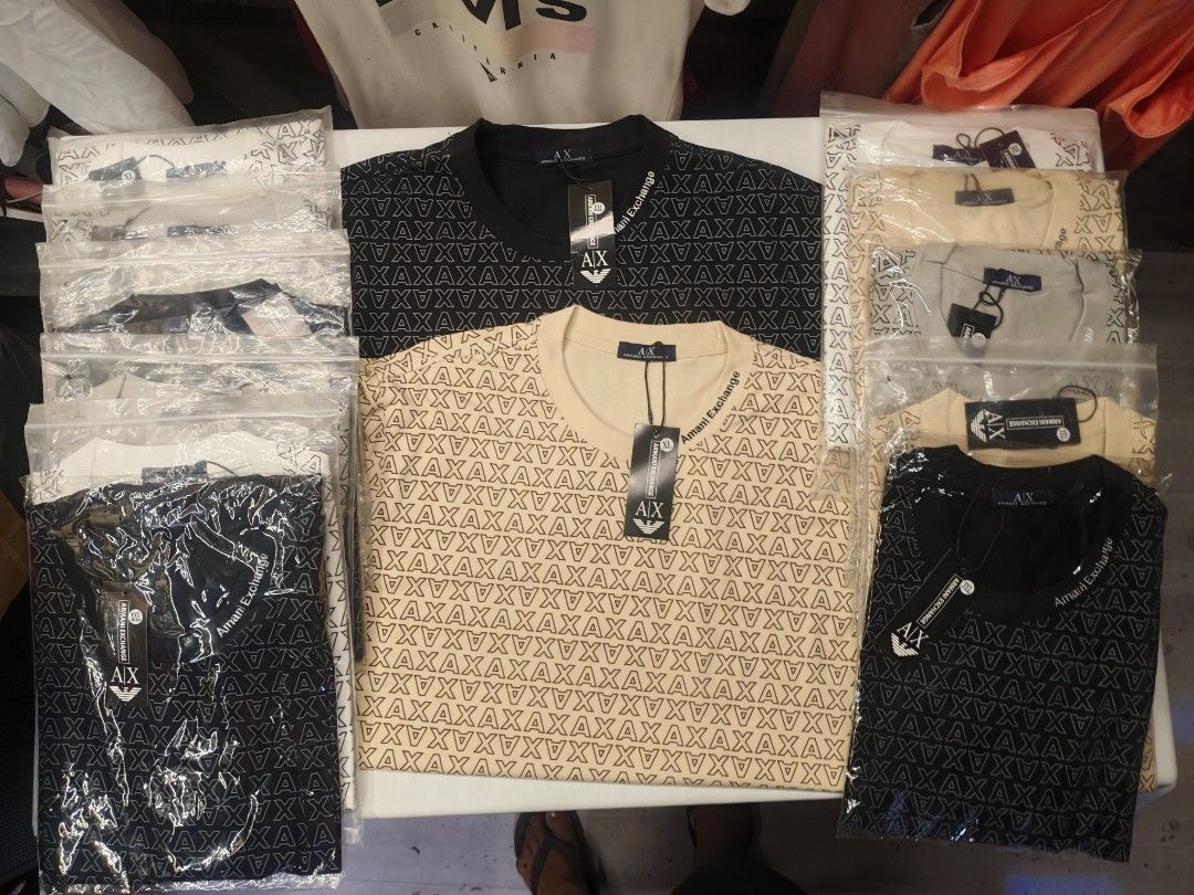 Armani Exchange AX T-Shirt (Category: Tshirts & Polo Shirts ) located in Quezon City. Submitted by rowem (Listing ID 1429479365, Image 1). Description: Armani Exchange AX T-shirts available in black beige, white and gray. Features an all-over AX logo pattern. Comes with original tags. The beige shirt has "Armani Exchange" printed on the neckline. Short-sleeved and likely made of a comfortable fabric. Sizes Available XL/XXL/XXXL.