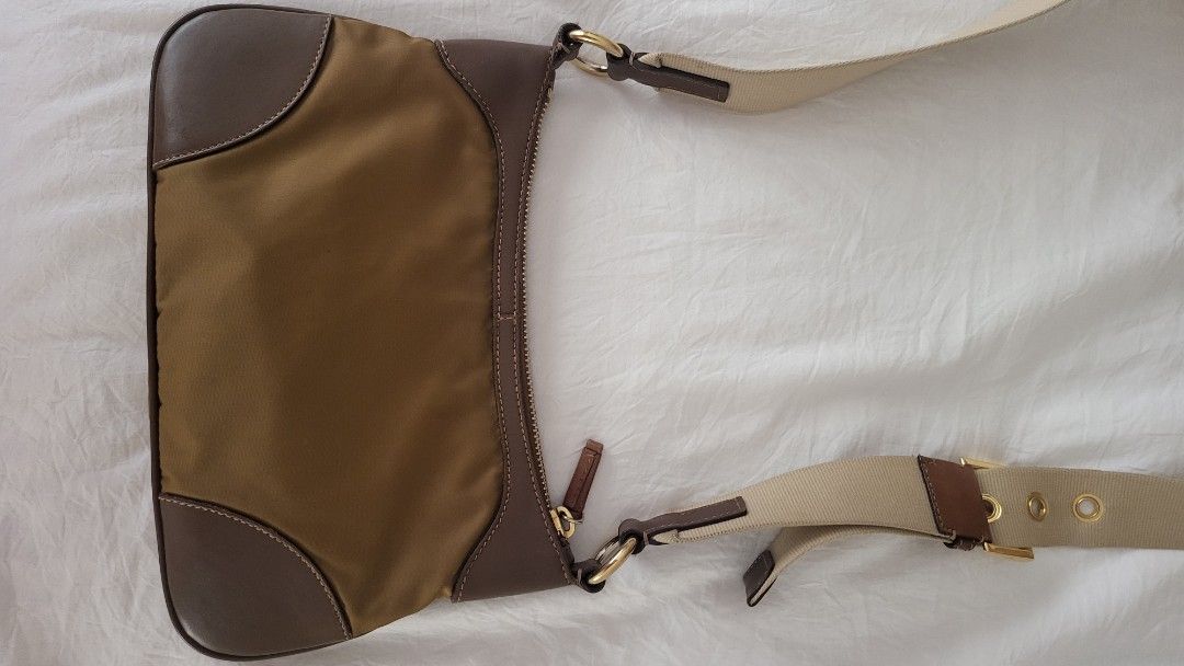 Authentic Prada Crossbody Bag (Category: Luxury Bags & Wallets) located in Quezon City. Submitted by bonching (Listing ID 1429598697, Image 3). Description: Prada shoulder bag features a nylon body with leather trim. It has a zip closure and an adjustable shoulder strap. The interior includes a Prada label and a serial number. The bag has a gold-tone hardware and a signature Prada triangle logo on the front. It has small stain at the inner bottom