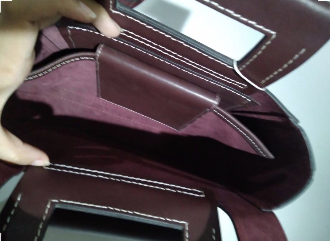 Celine Small Square Handbag Burgundy (Category: Luxury Bags & Wallets) located in Padre Garcia. Submitted by lucky_buelav (Listing ID 1429620770, Image 3). Description: Celine Small Square Handbag in burgundy. Features a unique square shape with a top handle and a flap closure. The bag has white stitching details and a small pocket on the front. Includes a dust bag. The interior has a small pocket. The style code is 184823DLG.28RO..