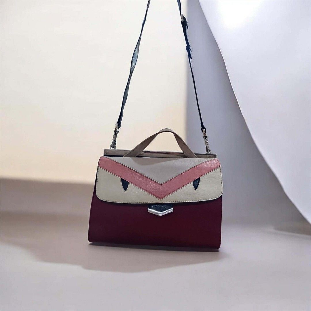 Fendi Monster Demi Jour Shoulder Bag Authentic (Category: Luxury Bags & Wallets) located in Tacloban City. Submitted by luxbag_ph (Listing ID 1429546238, Image 1). Description: Fendi Demi Jour shoulder bag with a unique monster eye design. Features a top handle and a detachable shoulder strap. The bag has a burgundy body with a cream and pink top panel. The interior has a leather lining and a magnetic closure. Includes Fendi branding on the hardw