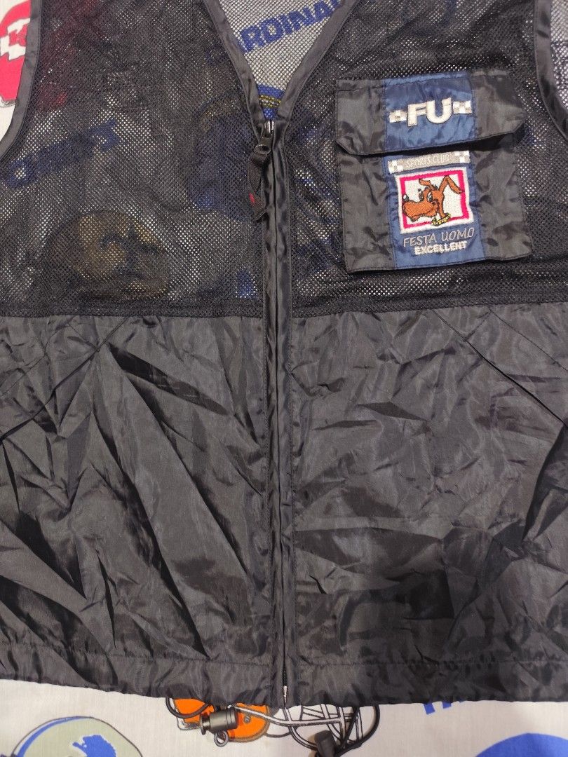 Festa Uomo Black Vest (Category: Vests) located in Baguio. Submitted by FRANKLIN (Listing ID 1429660146, Image 3). Description: Black vest from Festa Uomo. Features a zip closure and a pocket with a logo patch. The vest has a mesh upper section and a solid lower section. The size tag indicates a size M and the measurements are 22x25. The vest has a "FU" logo on the pocket..
