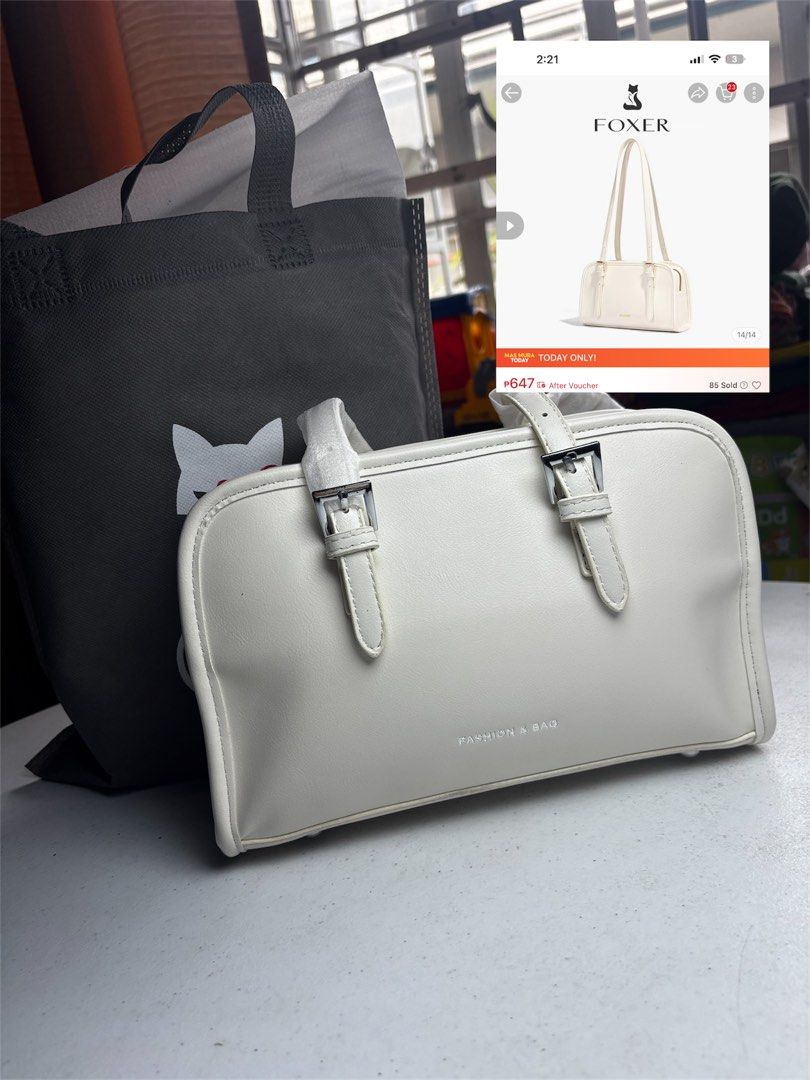 Foxer White Handbag (Category: Luxury Bags & Wallets) located in Angono. Submitted by hobwellph (Listing ID 1429528852, Image 1). Description: White handbag from Foxer. Features a rectangular shape with two handles and silver buckles. The words "FASHION & BAG" are printed on the front. Comes with a Foxer branded shoulder bag..
