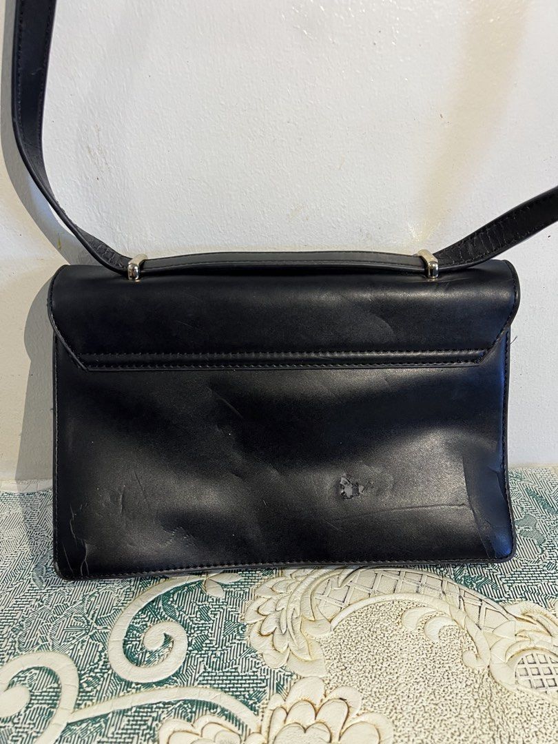 Hush Puppies Black Shoulder Bag (Category: Shoulder Bags) located in Makati City. Submitted by nicolaylay (Listing ID 1429504272, Image 3). Description: Black Hush Puppies shoulder bag with a flap closure. Features decorative embellishments on the front. Includes a top handle and a long shoulder strap. The bag has a gold-tone clasp and hardware. The back of the bag shows some wear. Flaw: See 3rd pic .