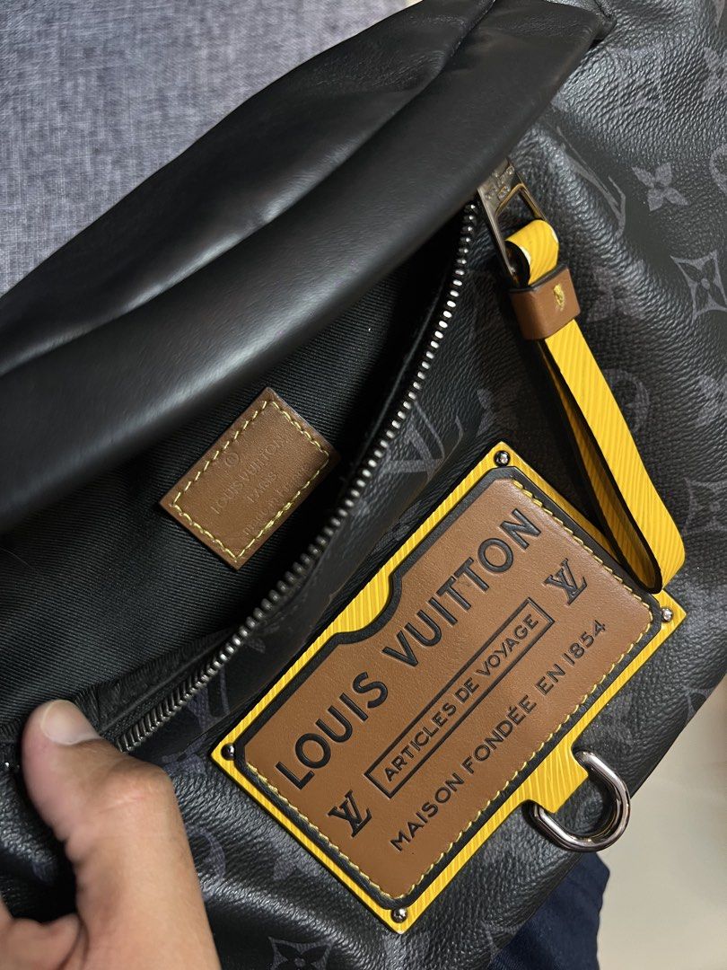 Louis Vuitton Monogram Eclipse Bumbag (Category: Luxury Bags & Wallets) located in Quezon City. Submitted by just.loveclub (Listing ID 1429653776, Image 2). Description: Louis Vuitton Bumbag in Monogram Eclipse canvas. Features a black leather body with the iconic LV monogram pattern. Includes a yellow and brown leather tag with the Louis Vuitton logo. The bag has a silver buckle and zipper. The interior has a small leather tag with the Louis Vui