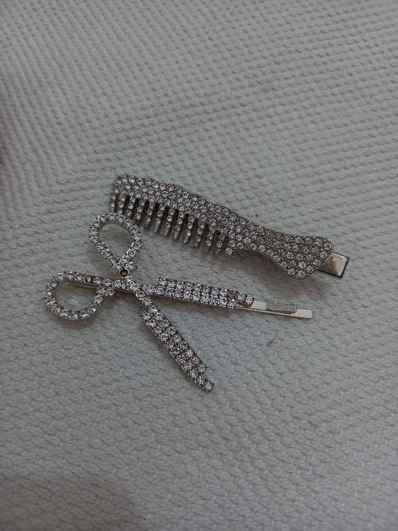 Rhinestone Hair Clips Set (Category: Hair Accessories) located in Tuguegarao City. Submitted by zenphoenix-7ad615 (Listing ID 1429550653, Image 2). Description: Set includes two hair clips: a comb-shaped clip and a scissors-shaped clip. Both clips are adorned with rhinestones. The comb clip has a silver finish, while the scissors clip has a silver finish with rhinestones. These clips are perfect for adding a touch of sparkle to any hairstyle..