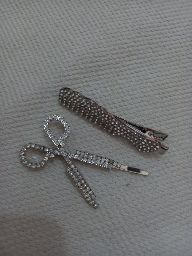Rhinestone Hair Clips Set (Category: Hair Accessories) located in Tuguegarao City. Submitted by zenphoenix-7ad615 (Listing ID 1429550653, Image 1). Description: Set includes two hair clips: a comb-shaped clip and a scissors-shaped clip. Both clips are adorned with rhinestones. The comb clip has a silver finish, while the scissors clip has a silver finish with rhinestones. These clips are perfect for adding a touch of sparkle to any hairstyle..