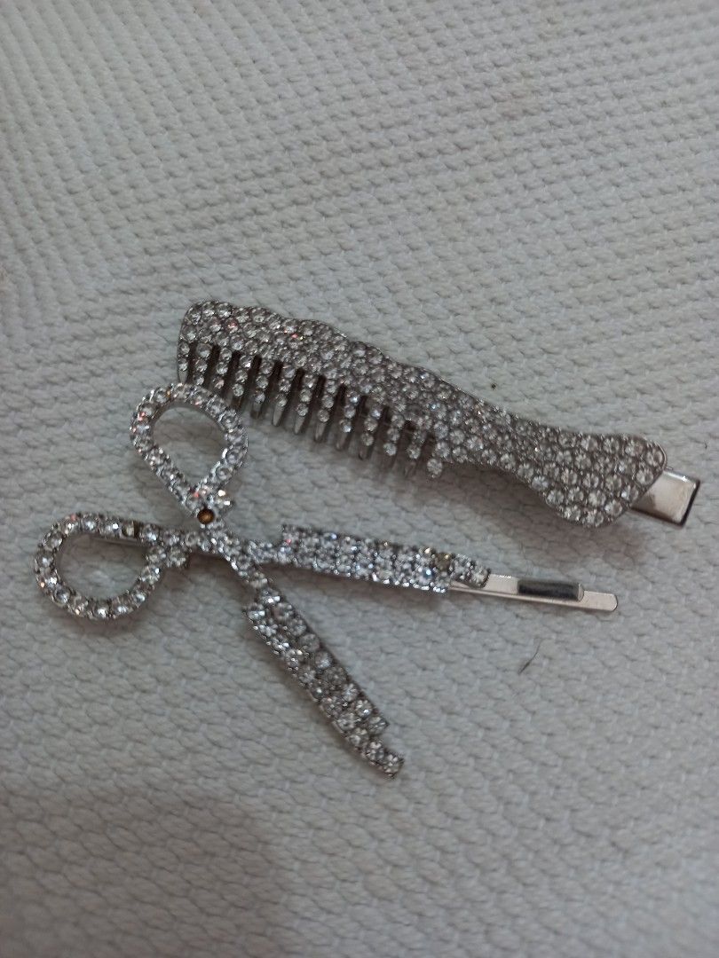 Rhinestone Hair Clips Set (Category: Hair Accessories) located in Tuguegarao City. Submitted by zenphoenix-7ad615 (Listing ID 1429550653, Image 3). Description: Set includes two hair clips: a comb-shaped clip and a scissors-shaped clip. Both clips are adorned with rhinestones. The comb clip has a silver finish, while the scissors clip has a silver finish with rhinestones. These clips are perfect for adding a touch of sparkle to any hairstyle..