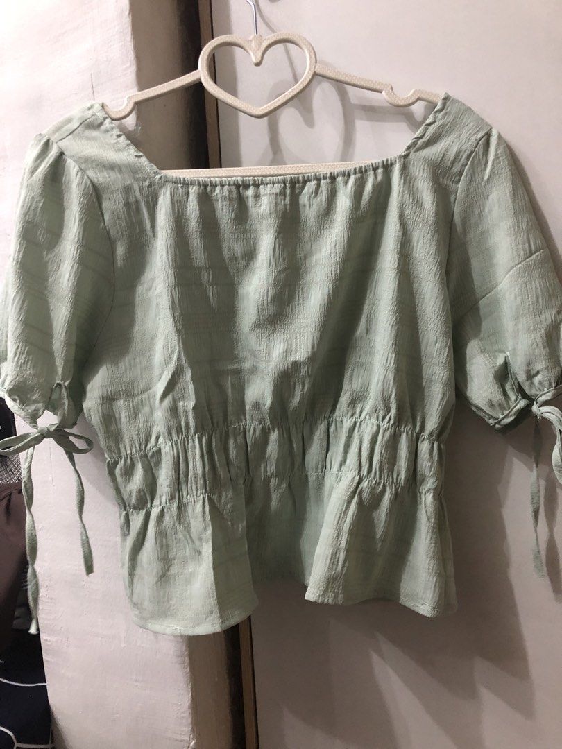 Square Neckline Top with Tie Sleeves (Category: Blouses) located in Pateros City. Submitted by downsizin (Listing ID 1429616179, Image 3). Description: With mini minimal stain‼️ Top features a square neckline and short sleeves with tie details. It has a gathered waistline and a slightly textured fabric. The top is a light green color. It is a versatile piece that can be dressed up or down..