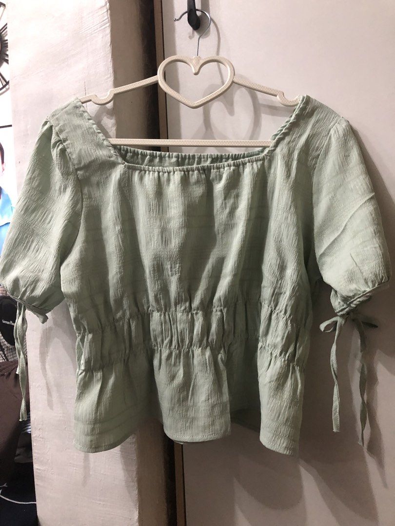 Square Neckline Top with Tie Sleeves (Category: Blouses) located in Pateros City. Submitted by downsizin (Listing ID 1429616179, Image 1). Description: With mini minimal stain‼️ Top features a square neckline and short sleeves with tie details. It has a gathered waistline and a slightly textured fabric. The top is a light green color. It is a versatile piece that can be dressed up or down..