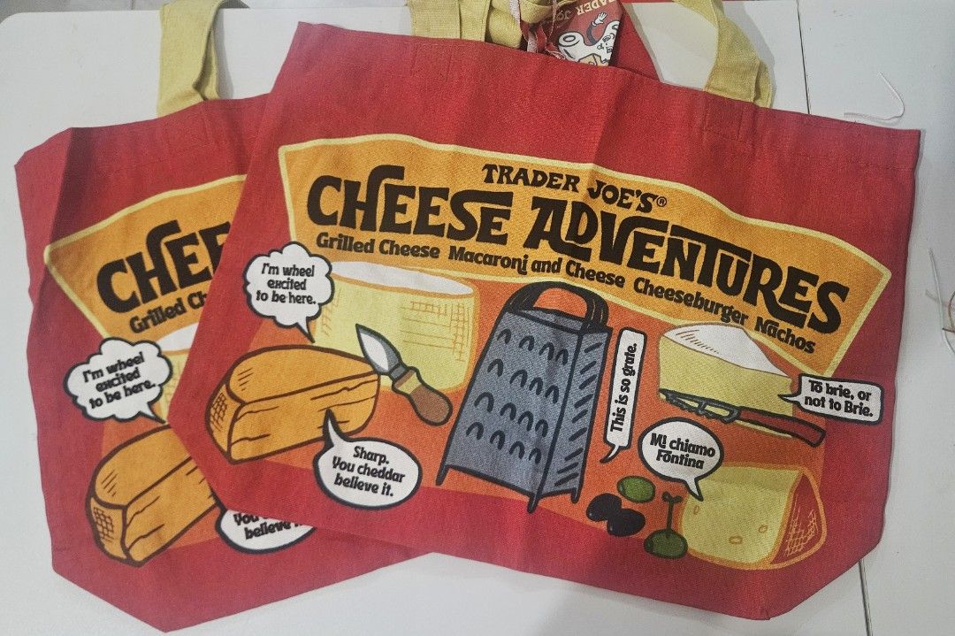 Trader Joe's Cheese Adventures Tote Bag (Category: Tote Bags) located in Quezon City. Submitted by miabelly (Listing ID 1429642675, Image 1). Description: Trader Joe's tote bag features a fun "Cheese Adventures" design. It's perfect for grocery shopping or carrying your essentials. The bag is red with a yellow and black graphic. It has a sturdy handle for easy carrying. A great reusable bag for any cheese lover!.