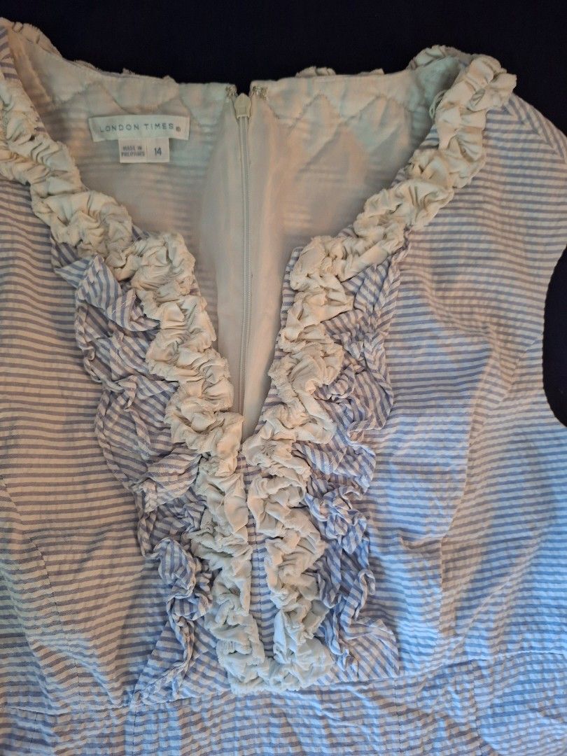 Branded Sleeveless Dress Size 14 (Category: Dresses) located in Mandaue City. Submitted by fsmfsm (Listing ID 1431209416, Image 2). Description: Sleeveless dress from London Times features a blue and white striped pattern. It has a V-neckline with ruffle detailing. The dress is a size 14 and has a zipper closure at the back. -like new - 38.5" x 20" from armpit to armpit - powder blue and white.