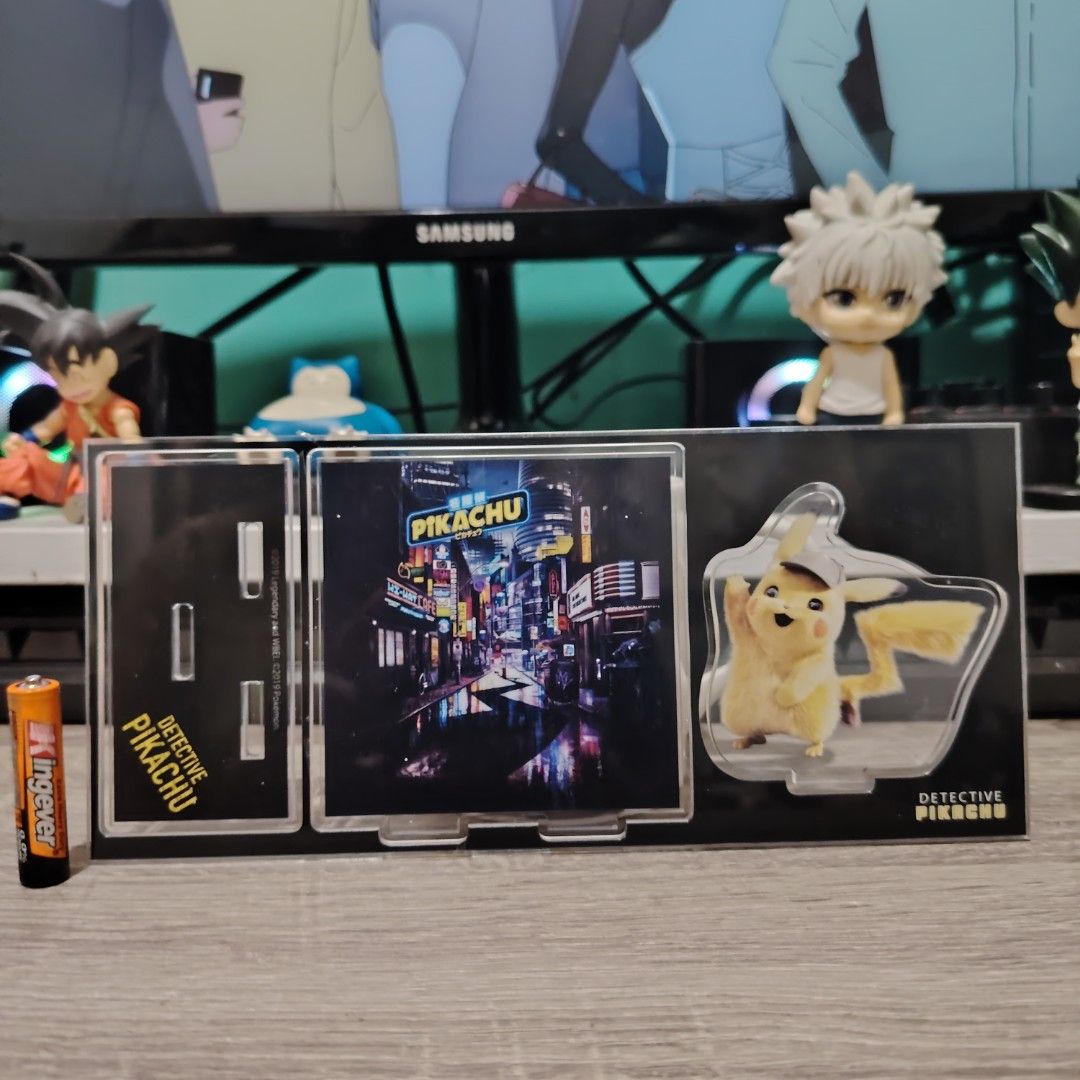 Detective Pikachu Display Stand (Category: Figurines & Statues) located in Bulacan. Submitted by qilyuartstudio (Listing ID 1431275014, Image 1). Description: Display stand features Detective Pikachu. It has a black base with three sections: a slot for a photo, a slot for a small item, and a Pikachu figure. The stand is designed to hold small items and photos. Perfect for any Detective Pikachu fan!.