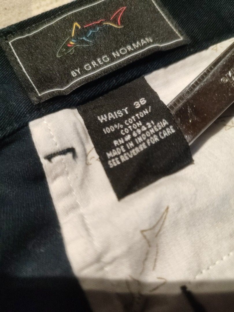 Greg Norman Golf Pants - Waist 36 (Category: Trousers) located in Baler. Submitted by onlyhuman_67 (Listing ID 1431349555, Image 1). Description: This is a pre-owned item but in very good condition. Picture may differ from actual color due to lighting. - Greg Norman golf pants - Size: 36 - Material: 100% cotton - Closure: Button - Design: Embroidered shark logo on pocket - Origin: Made in Indonesia - Color: Dark Navy.