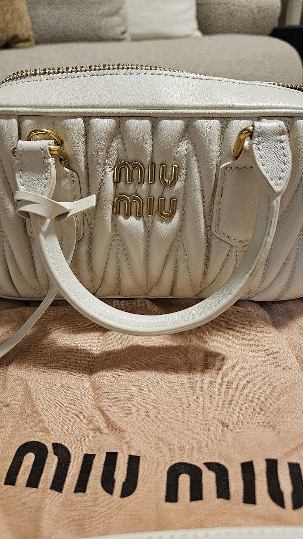 Miu Miu Matelassé Mini Bag (Category: Luxury Bags & Wallets) located in Manila. Submitted by maria28isabelle (Listing ID 1431182294, Image 2). Description: Miu Miu Matelassé mini bag in white. Features a top handle and a detachable shoulder strap. Includes a dust bag and a tag. The bag has a quilted design with gold-tone hardware and a zipper closure. The Miu Miu logo is visible on the front and the zipper..