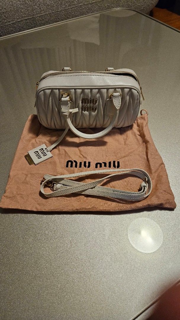 Miu Miu Matelassé Mini Bag (Category: Luxury Bags & Wallets) located in Manila. Submitted by maria28isabelle (Listing ID 1431182294, Image 1). Description: Miu Miu Matelassé mini bag in white. Features a top handle and a detachable shoulder strap. Includes a dust bag and a tag. The bag has a quilted design with gold-tone hardware and a zipper closure. The Miu Miu logo is visible on the front and the zipper..
