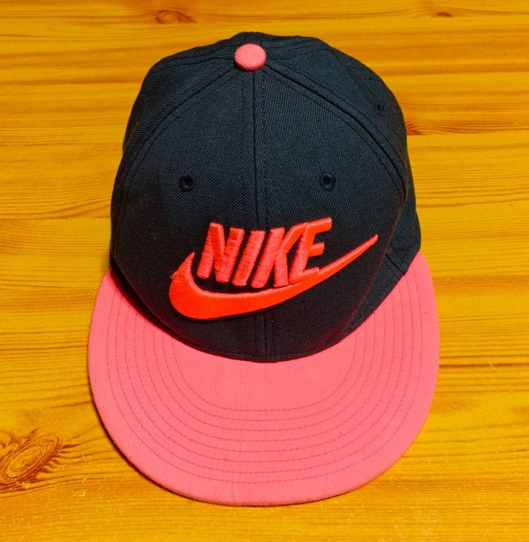 Nike True Cap (Category: Caps & Hats) located in Manila. Submitted by caps08 (Listing ID 1431232581, Image 2). Description: Nike True cap features a black crown with a pink brim. The Nike logo is prominently displayed on the front. The cap has a snapback closure. The tag indicates it is made in China. The interior features the Nike True logo and "Engineered to the Exact Specifications of Championship Athletes" printed on the lining..