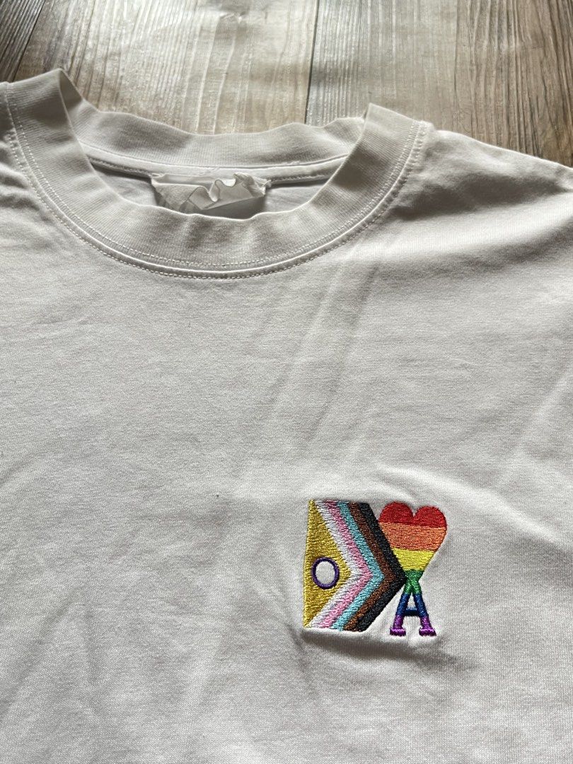 AMI Alexandre Mattiussi Pride T-shirt (Category: Tshirts & Polo Shirts ) located in Manila. Submitted by thriftnipapi7 (Listing ID 1431552912, Image 2). Description: White AMI Alexandre Mattiussi T-shirt with a small embroidered patch on the chest. The patch features a heart and the letters "A" and "M". The shirt has a crew neck and short sleeves. Made in Portugal..