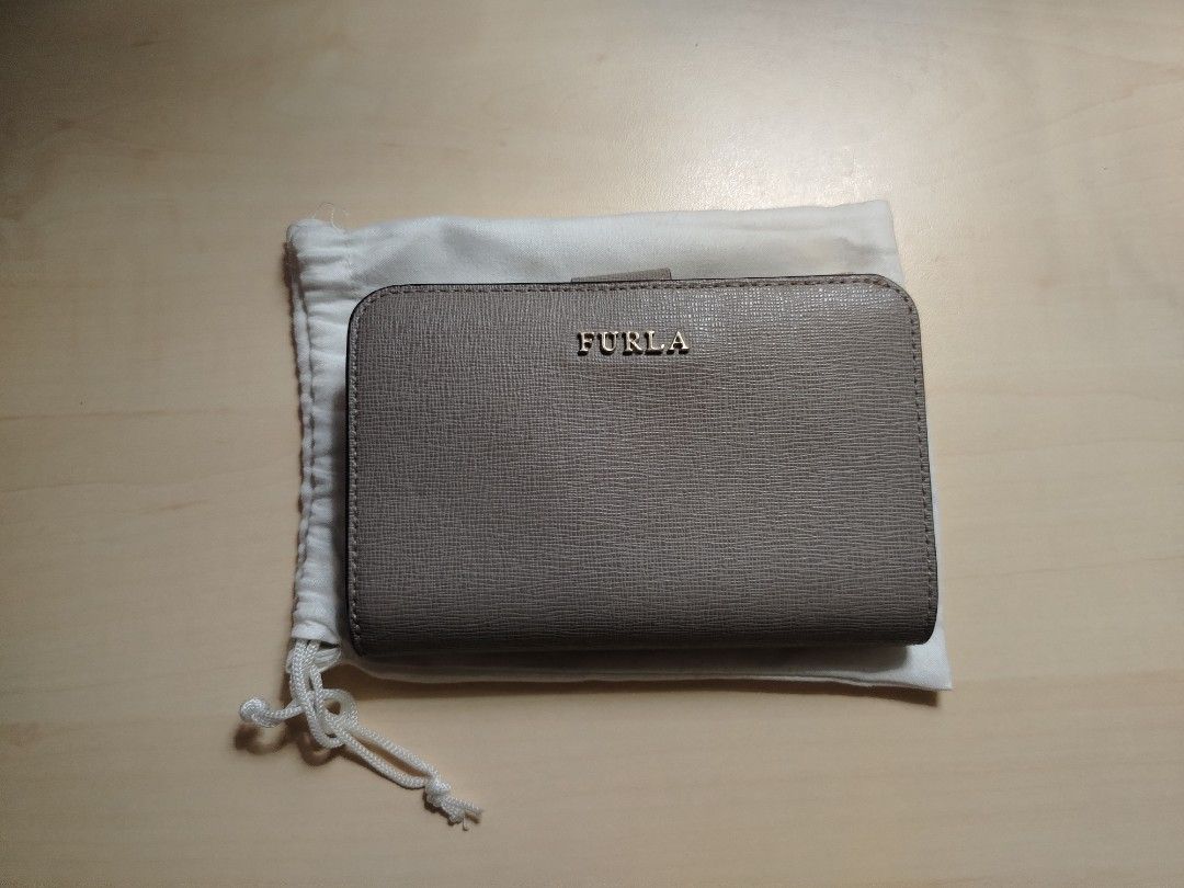 Furla Compact Wallet (Category: Luxury Bags & Wallets) located in Caloocan City. Submitted by jpygoodies (Listing ID 1431558155, Image 1). Description: - Furla wallet in a neutral taupe color - Compact and easy to carry - Features both zip-around and snap closures for security - Includes original dust bag - Genuine Furla logo visible - Crafted from textured leather.