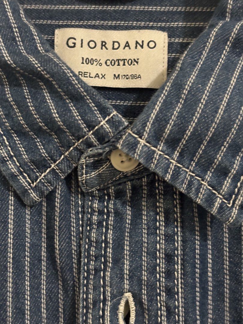Giordano Striped Denim Shirt (Category: Formal Shirts) located in Pasig City. Submitted by kathB (Listing ID 1431539105, Image 3). Description: Giordano men’s denim shirt (size M) in a relaxed fit, featuring vertical white stripes, contrast stitching, and unique double chest pockets. Made from 100% cotton with a button-down front. Oversized on petites since it’s men’s sizing. I usually wear a women’s XL and this fits just right. Measurement (L x 