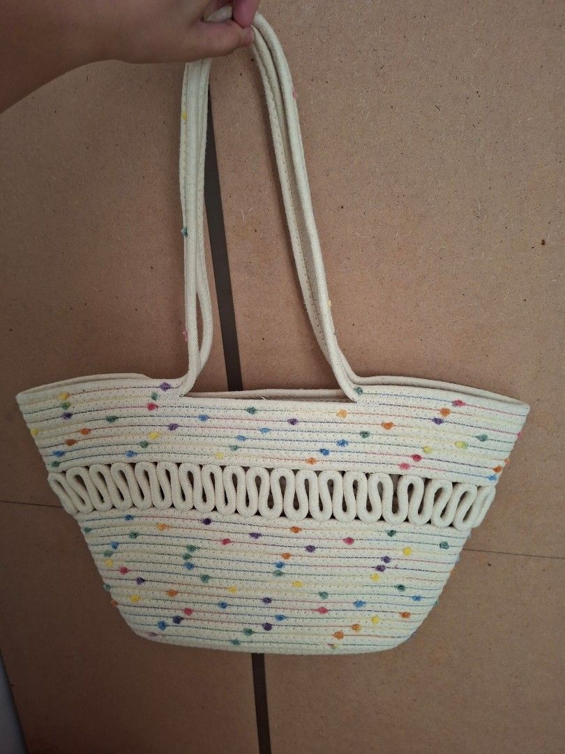 Summer Beach Bag (Category: Tote Bags) located in Pasig City. Submitted by khaid (Listing ID 1431434750, Image 1). Description: Handbag features a woven design with colorful accents. It has two handles and a spacious interior. The bag is made of a cream-colored material with a decorative border..