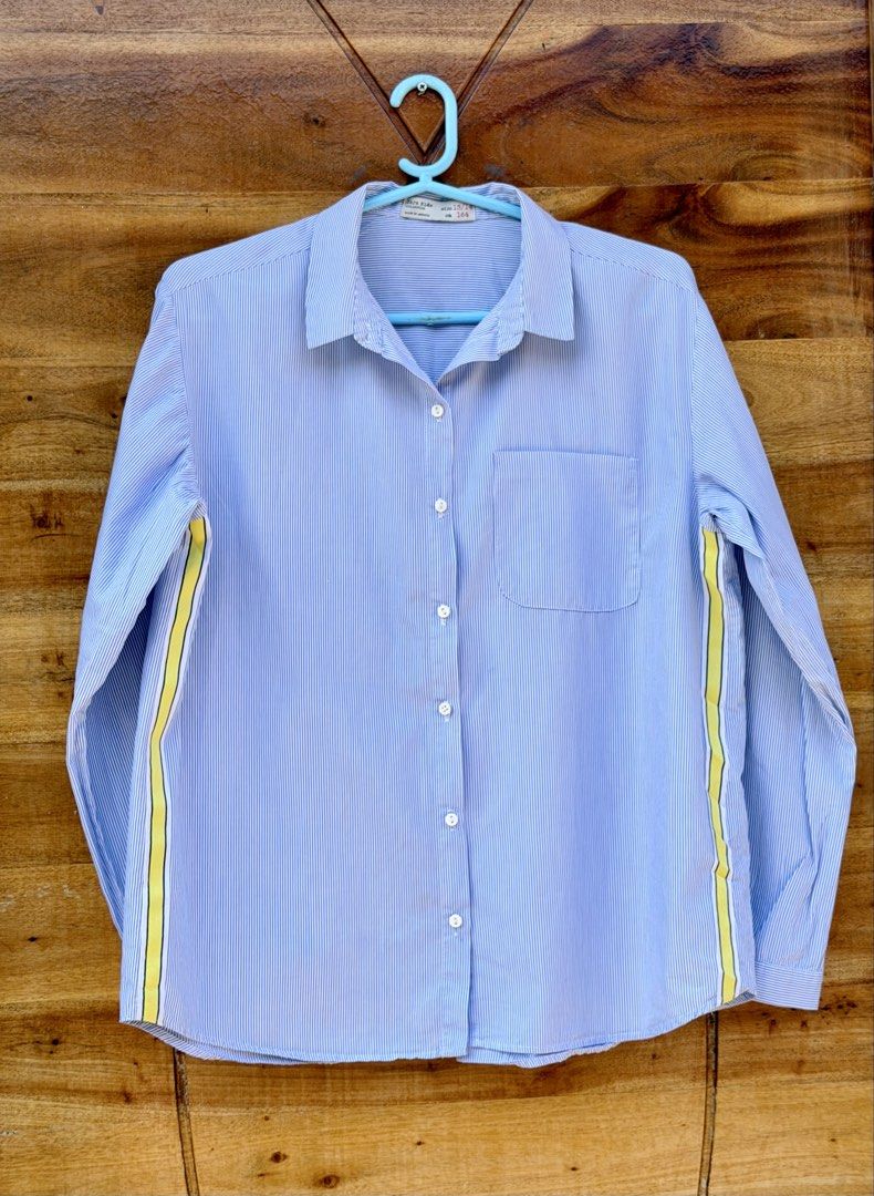 Zara Kids Striped Long Sleeves (Category: Babies & Kids Fashion) located in Cavite. Submitted by peppermintsss (Listing ID 1431435307, Image 2). Description: - Zara Kids striped shirt - Features a chest pocket - Classic collar and button-down closure - Color: Blue and white stripes with yellow side stripes - Size: 13/14 (164cm) - Made in Morocco ‼️Bust: 20” ‼️ Length: 24” 🛵 SF will be shouldered by the buyer.