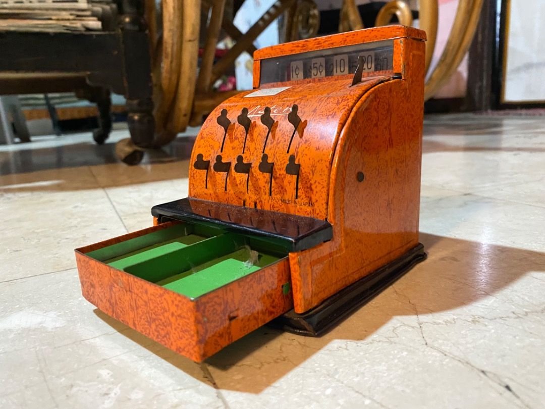 Aster Vintage Toy Cash Register (Category: Vintage Collectibles) located in Manila. Submitted by waltdisney10 (Listing ID 1431683158, Image 3). Description: - Vintage Aster toy cash register tin - Bright orange body with black base - Features coin slots for different denominations - Includes a functional drawer - Made in Japan.