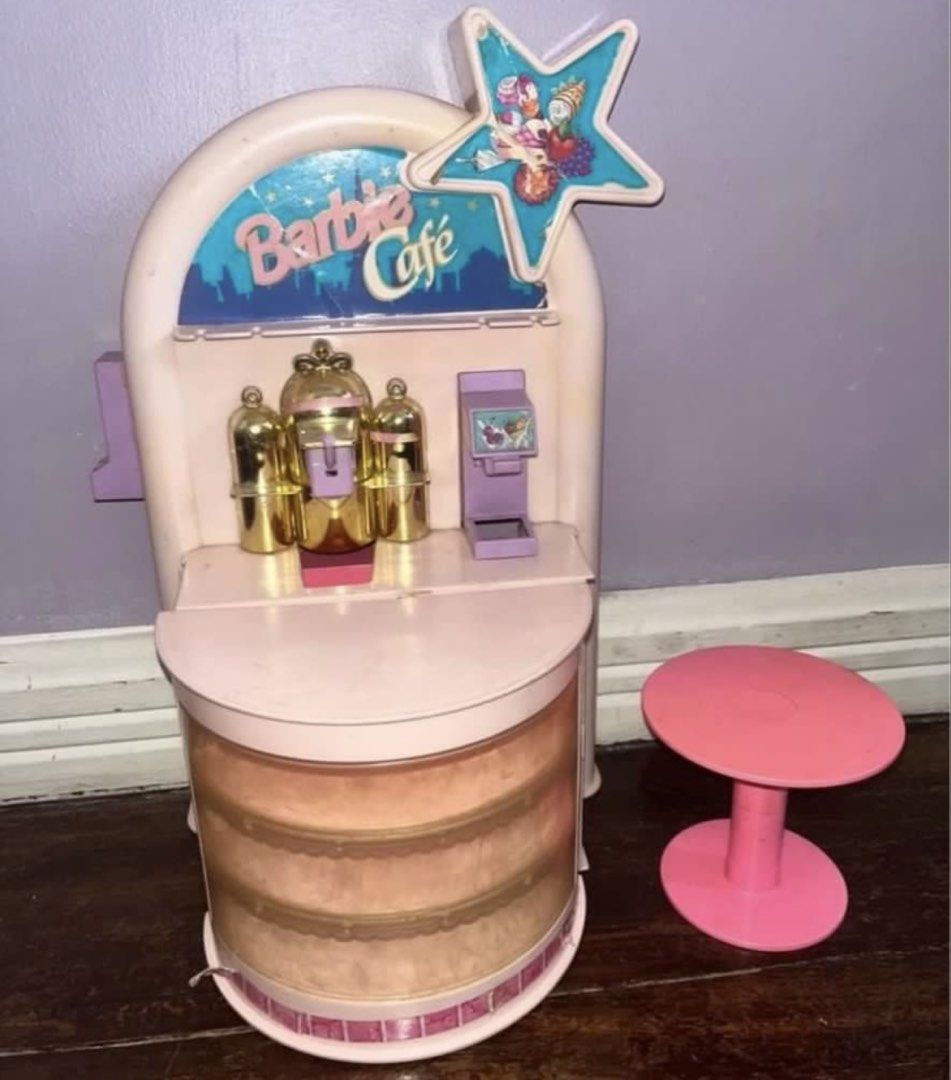 Barbie Vintage Cafe (Category: Kids Toys) located in Rizal. Submitted by cassappl (Listing ID 1431675804, Image 2). Description: - Vintage Barbie Cafe playset - Includes cafe structure with counter, shelves, and serving area - Comes with accessories: table, chairs, cups, saucers, serving trays - Features coffee machine and cafe-themed details - Pink and gold color scheme.