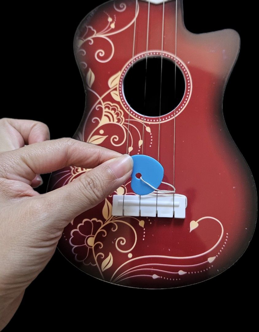 Decorative Red Ukulele Toy (Category: Musical Instruments) located in Makati City. Submitted by xzyche (Listing ID 1431608245, Image 3). Description: - Red ukulele with floral accents - Includes a blue pick - Comes with a carrying case - Small size.